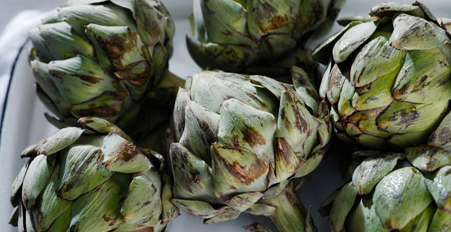a bunch of artichokes sitting on top of a white tray.