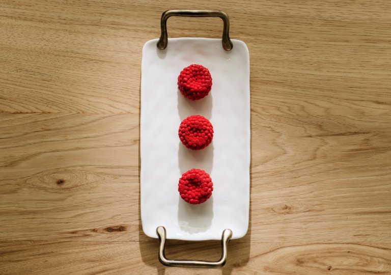three red crocheted balls on a white plate.