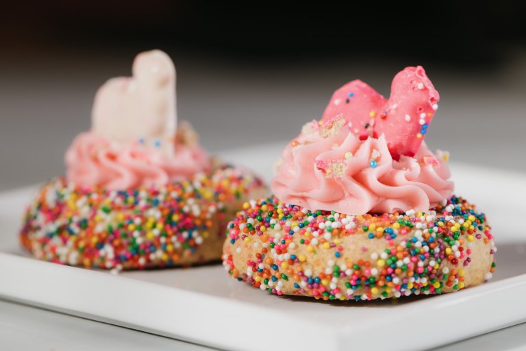 two donuts with pink frosting and sprinkles.