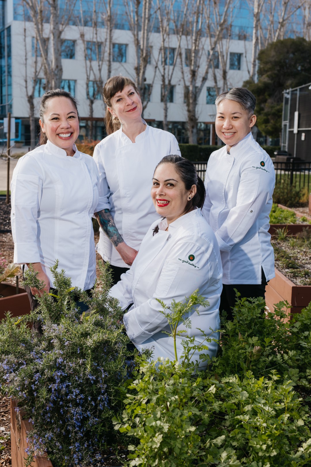 a group of women standing next to each other in a garden.