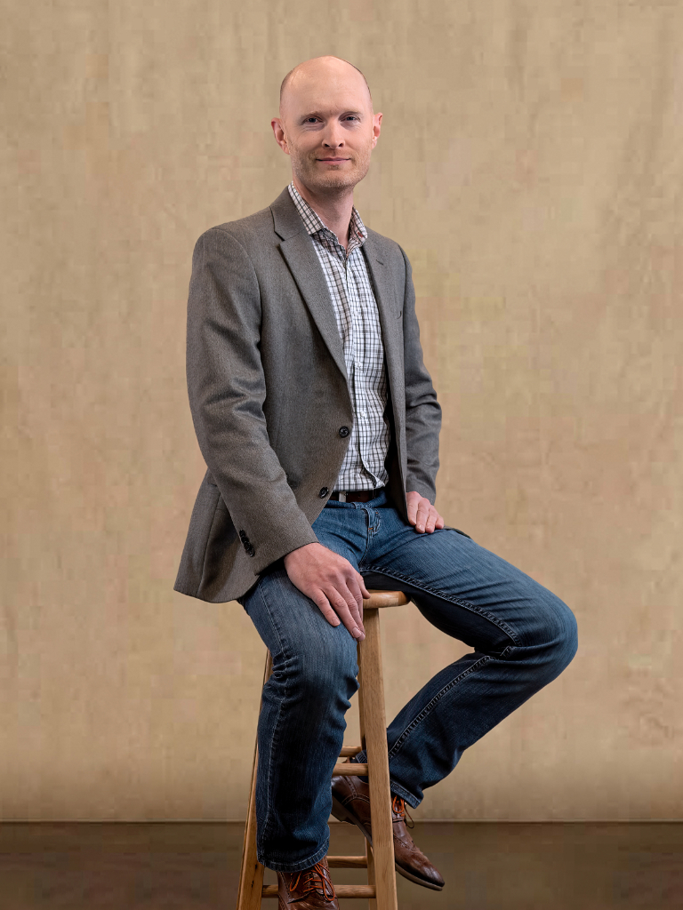 a man sitting on top of a wooden stool.