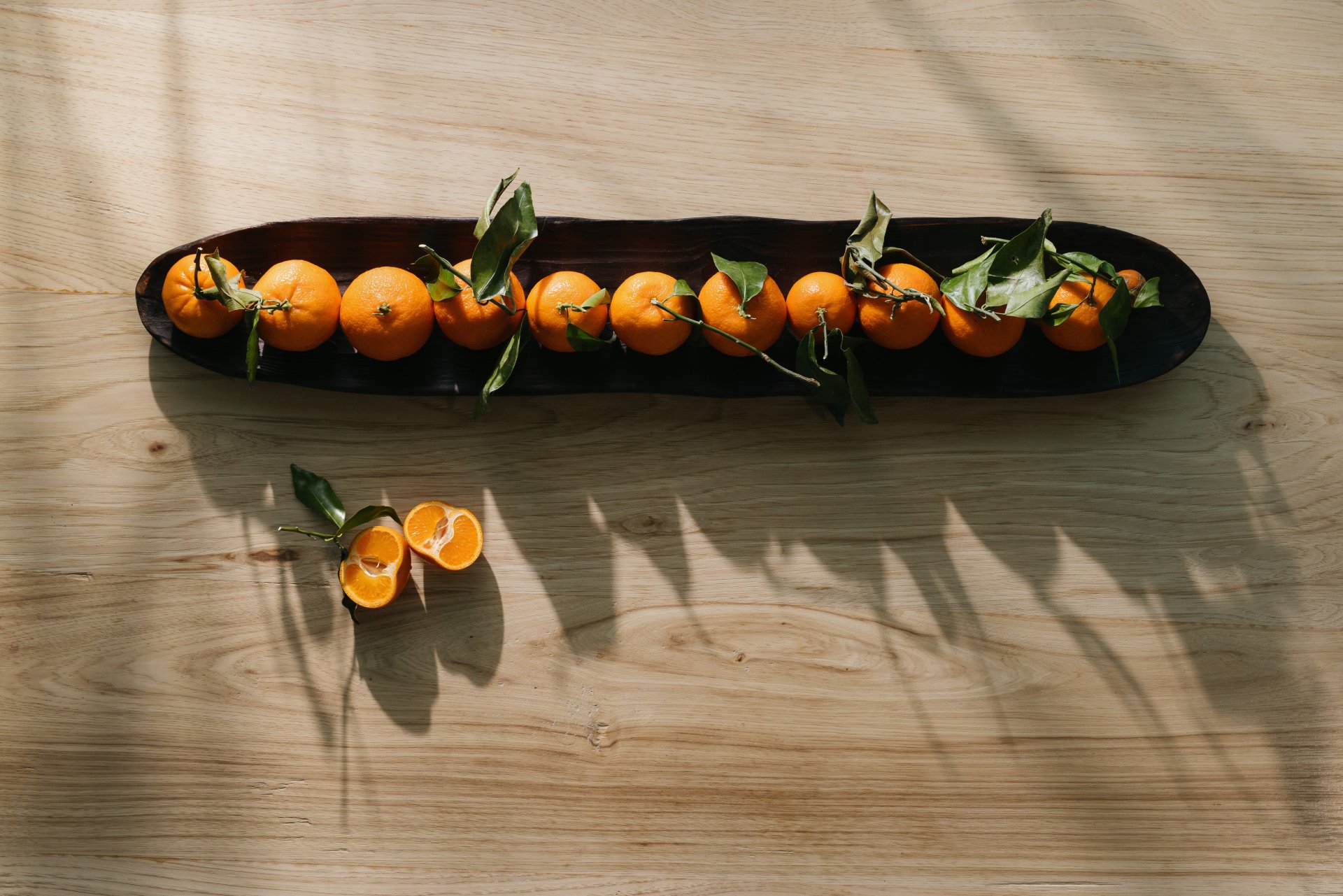 A tray of tangerines on a wooden table.